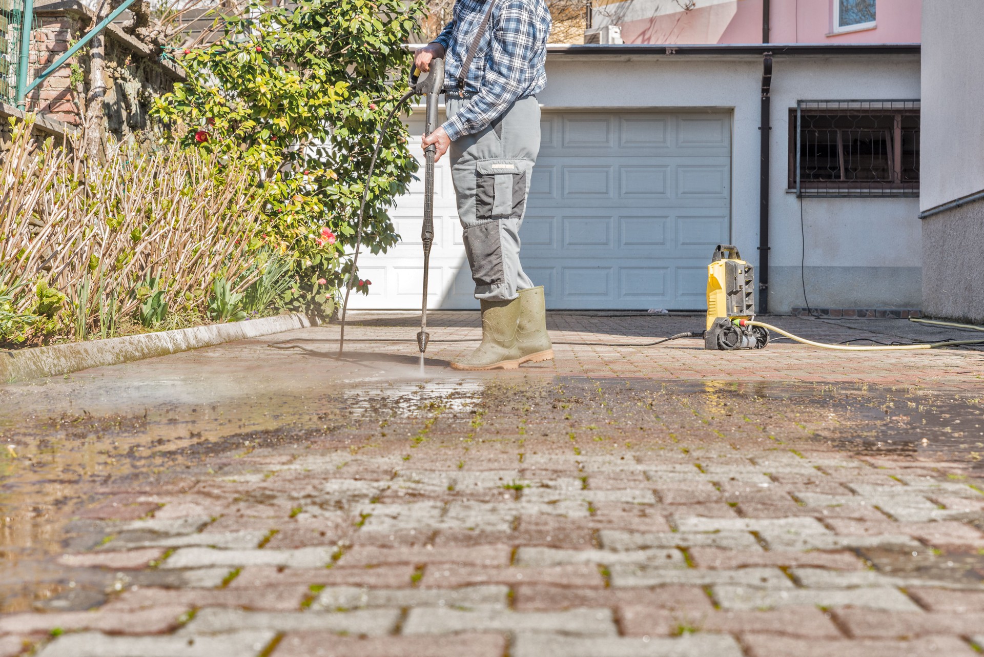 Active Senior Man Using High Pressure Washer to Clean the Entrance