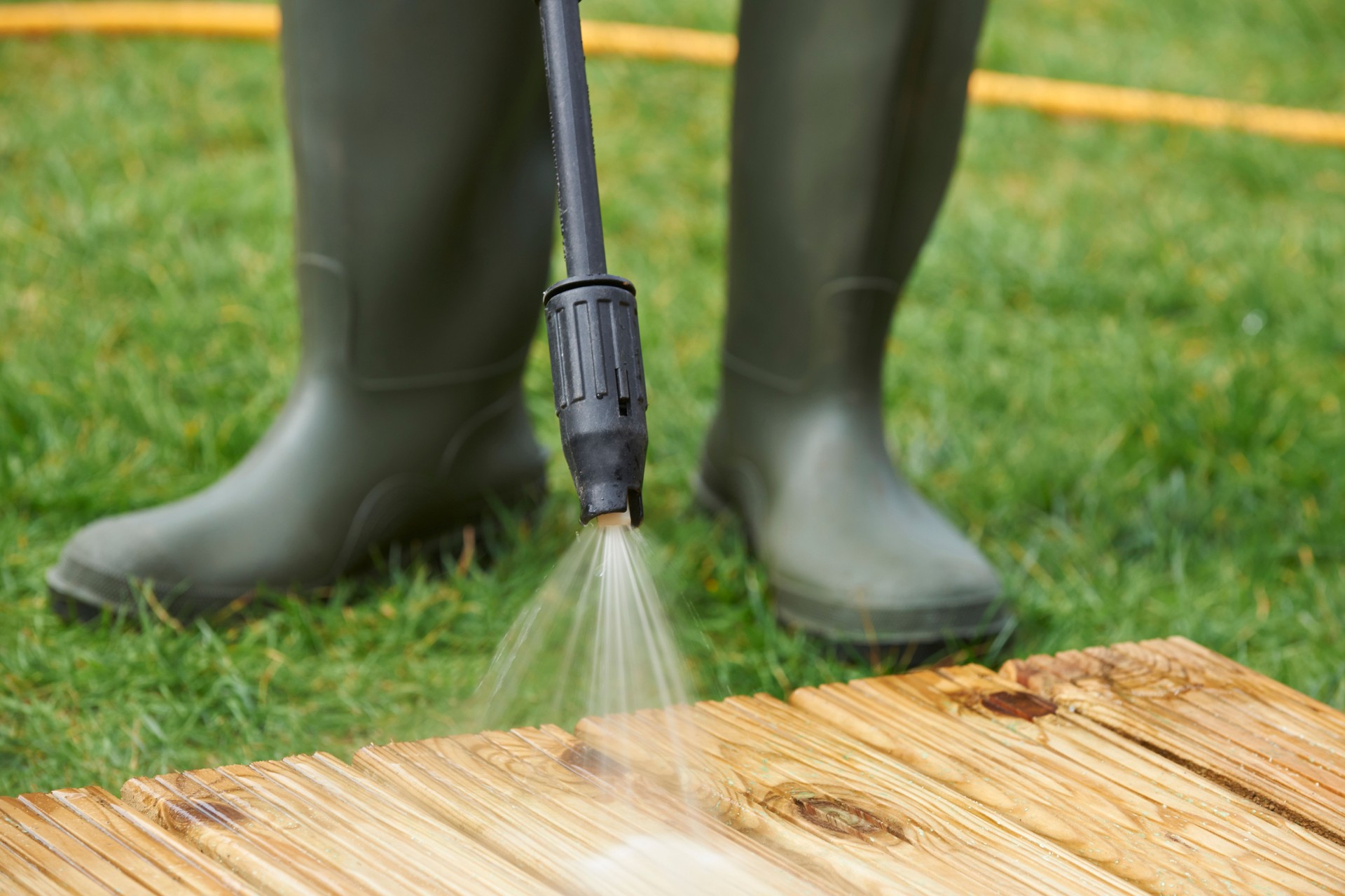 Man Washing Wooden Decking With Pressure Washer