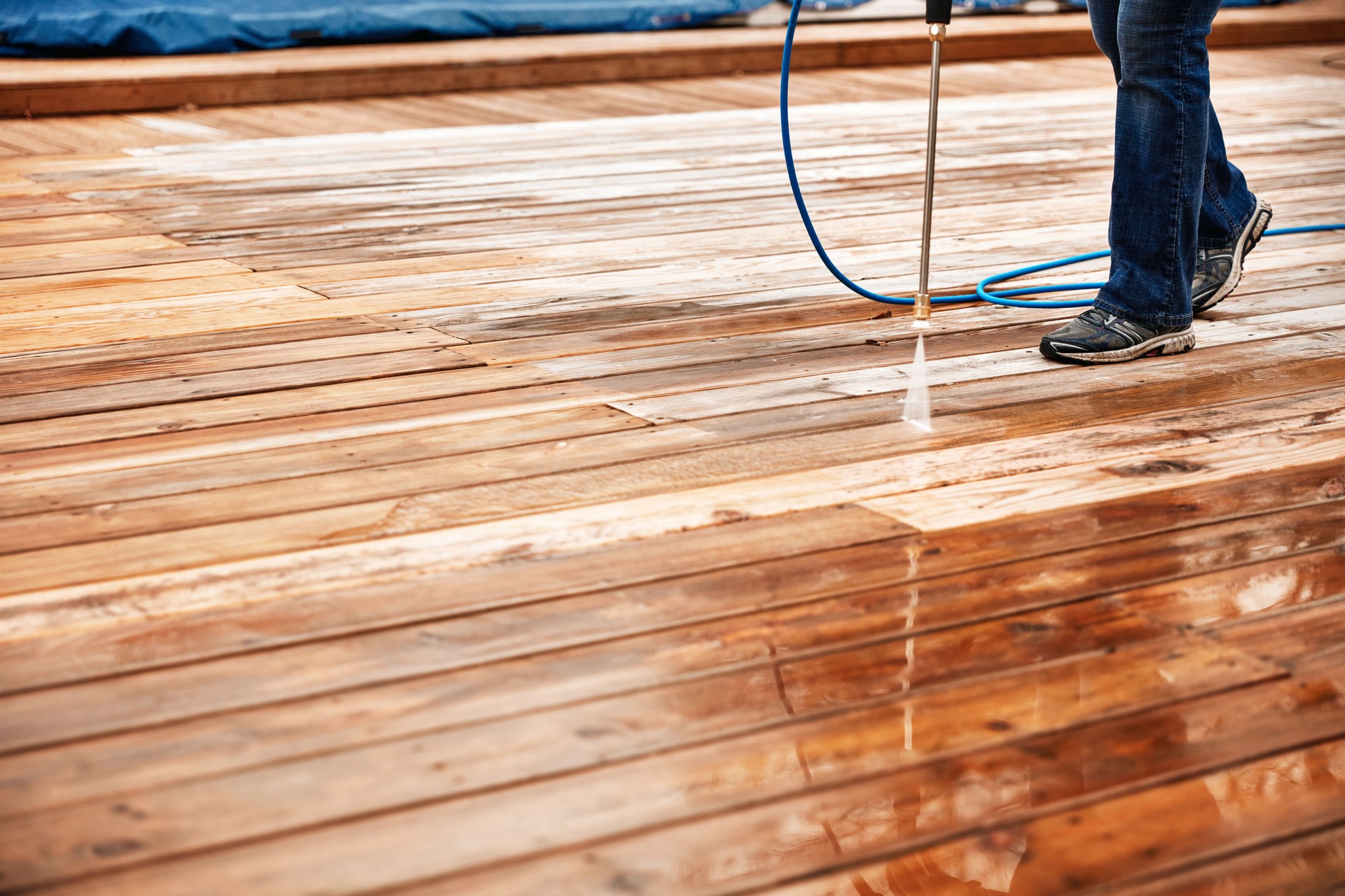 Woman Cleaning Wooden Terrace With A High Water Pressure Cleaner